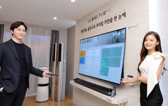 모델들이 LG 시그니처 올레드 TV W 제품으로 집안 인공지능 가전을 한눈에 확인하고 제어할 수 있는 '인공지능 홈보드' 기능을 소개하고 있다. <LG전자 제공>